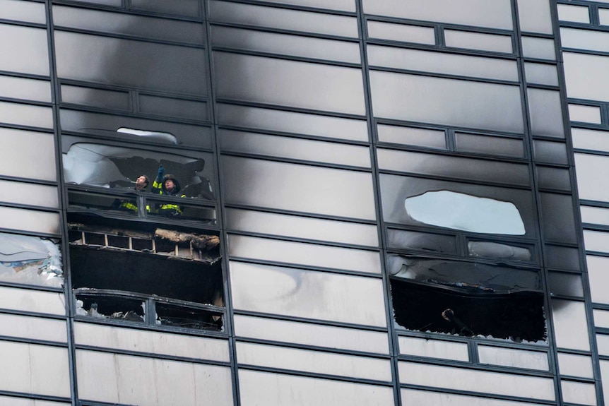 Firefighters look out from the window of a fire damaged apartment in Trump Tower in New York.