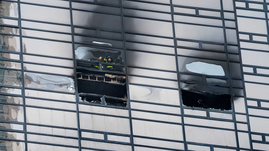 Firefighters look out from the window of a fire damaged apartment in Trump Tower in New York.
