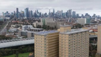 Two public housing towers with the Melbourne city skyline in the background.