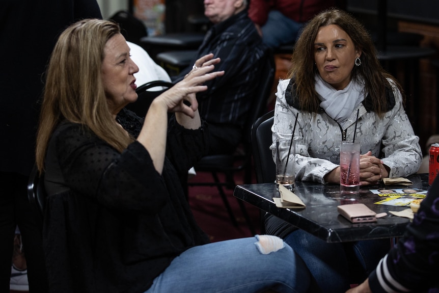 Tammy Tyrell sits at a table and chats with Jacqui Lambie.