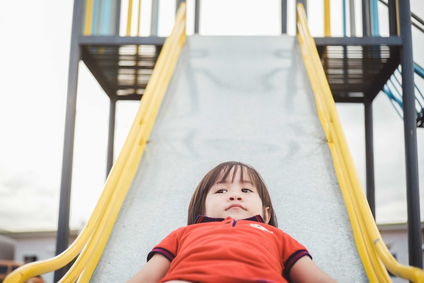 Cute little boy about three years old on a playground slide