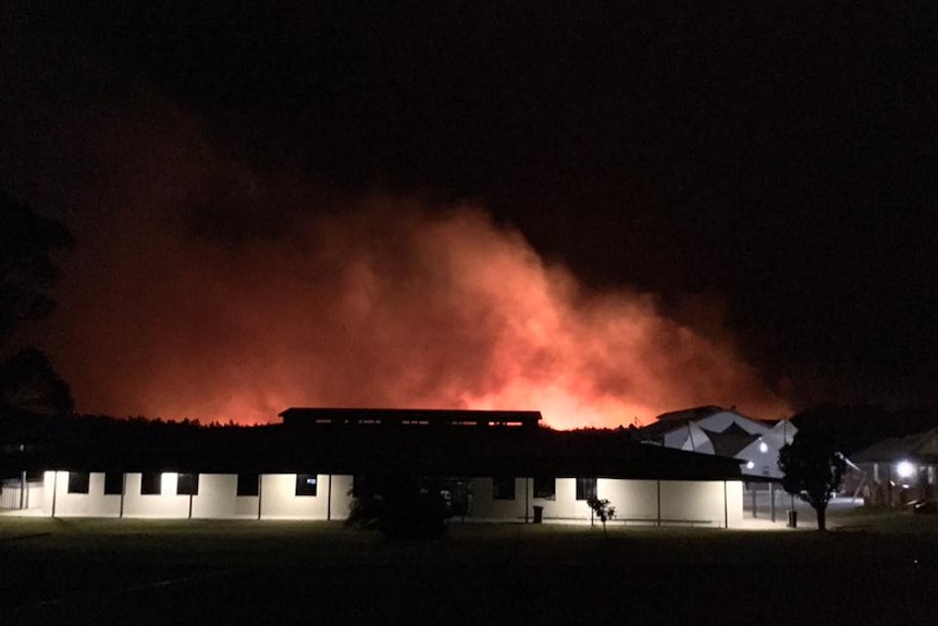 A fire behind a building at night.
