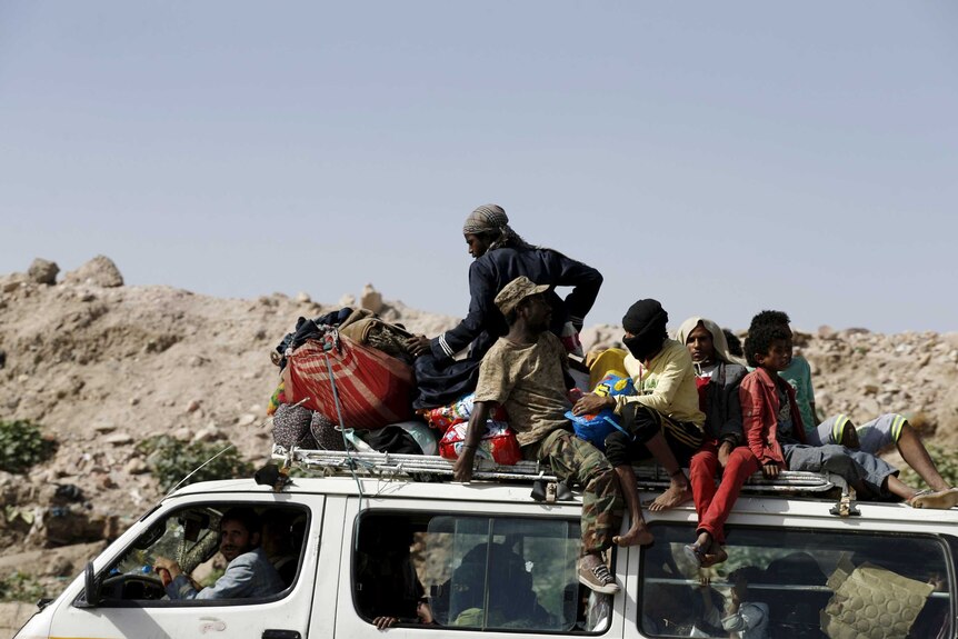 People ride atop a van as they flee their homes