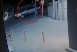 A silver car seen driving down the road in grainy footage