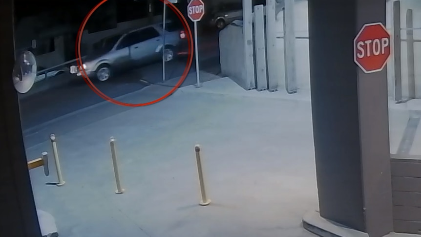 A silver car seen driving down the road in grainy footage