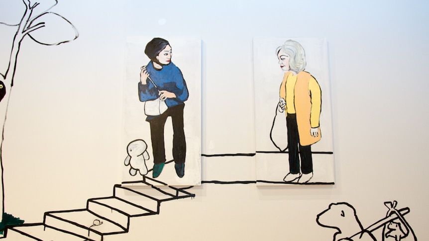 A painting on a white wall of two women looking at each other