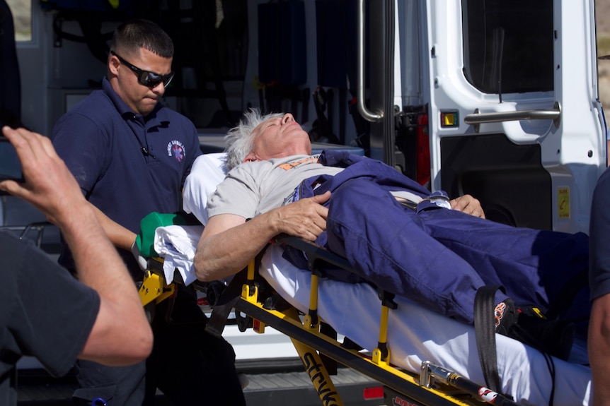 Man on a stretcher being transferred into an ambulance.