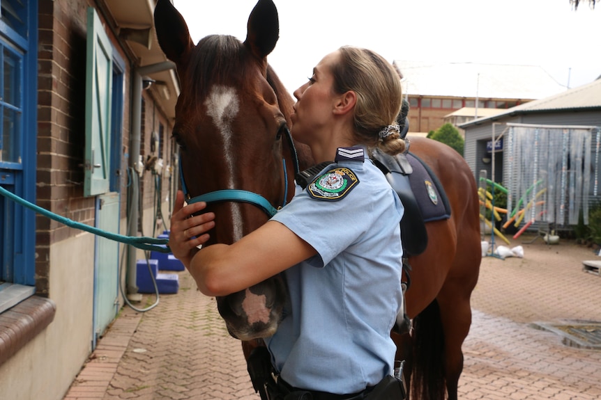 A woman stands hugging a horse