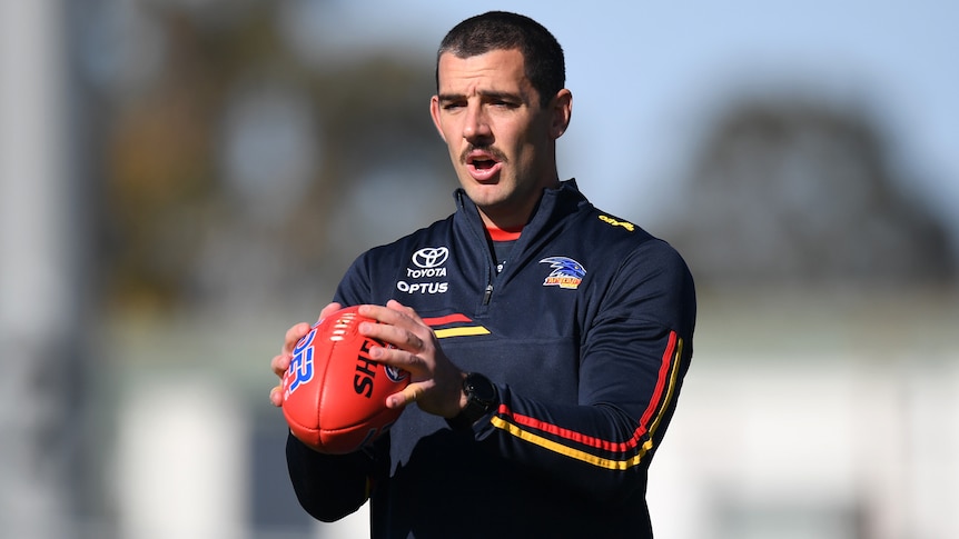 Taylor Walker shapes to kick and AFL ball while wearing Adelaide Crows gear.