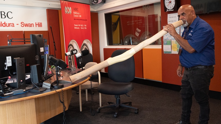 A man playing the didgeridoo in a radio studio