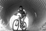 man on mountain bike coming through a tunnel