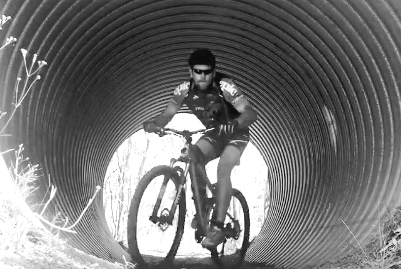 man on mountain bike coming through a tunnel