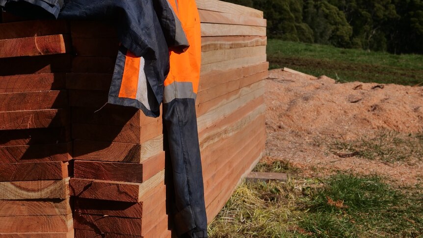 A stack of wooden planks with a fluoro jacket resting on top.