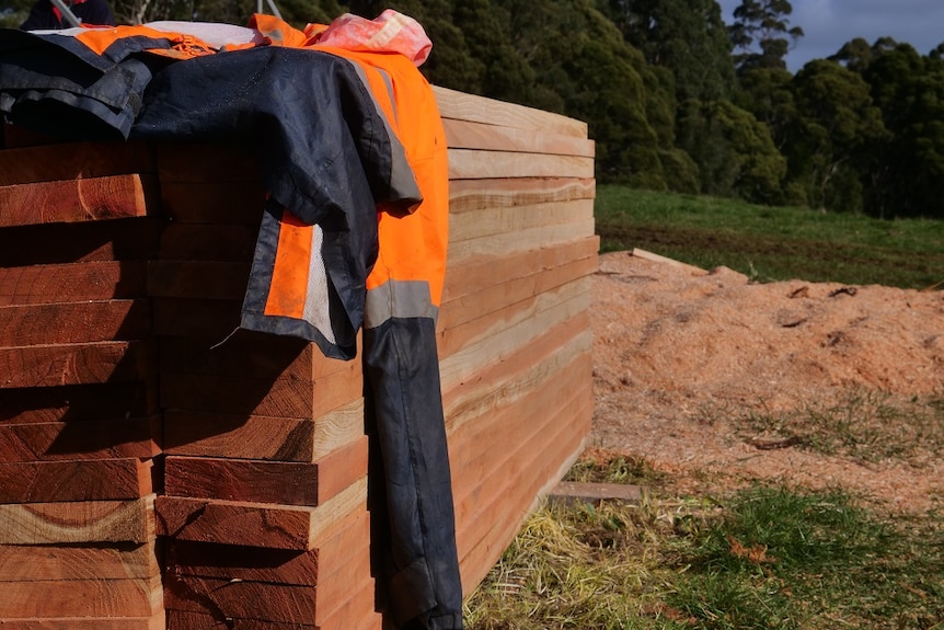 A stack of wooden planks with a fluoro jacket resting on top.