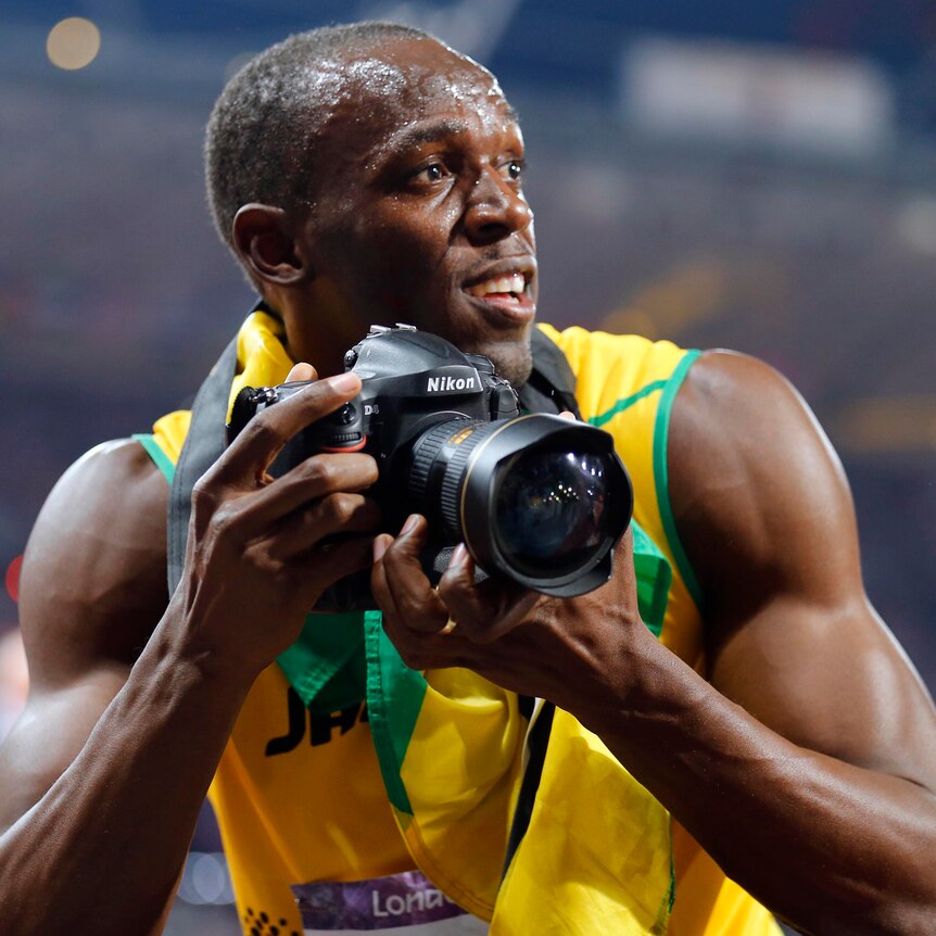 Usain Bolt uses a photographer's camera to take photos after he won the men's 200m final.