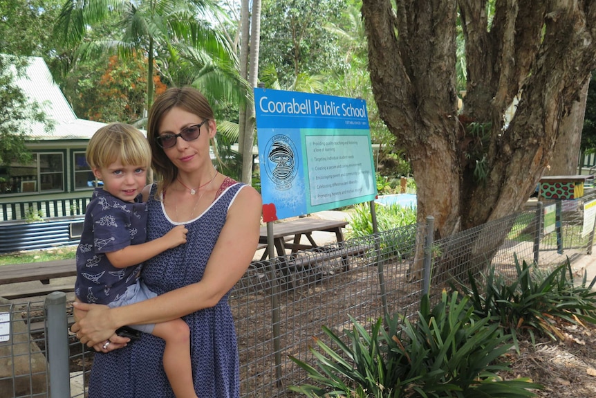 A mother holds her son outside a rural primary school.