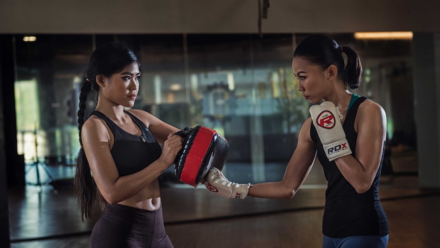 Two women demonstrate practice sparring at a self defence class.