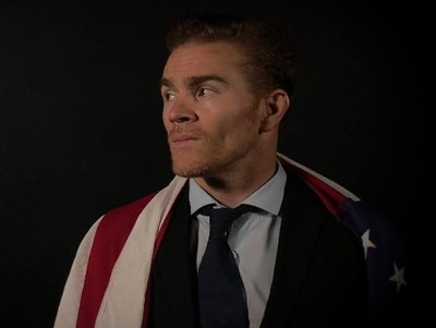 A portrait of Jordan Goudreau with the American flag draped over his shoulders.