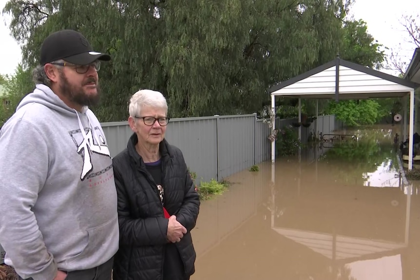 Lynn stands with her son in her flooded yard