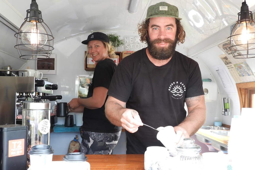 Two people making coffee in a little caravan