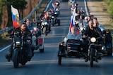 Putin rides beside the head of the motorcycle club "Night Wolves" as the rest of the gang follow behind.