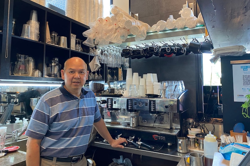 A man standing in front of a coffee machine in a cafe