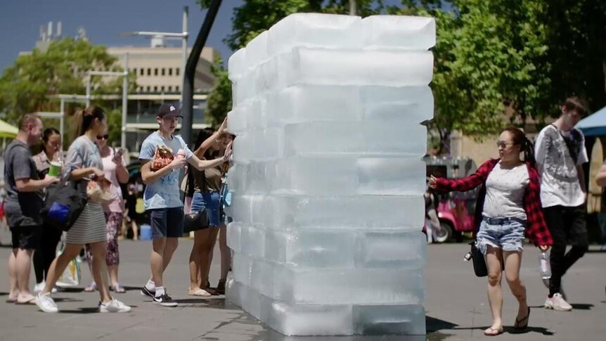 People surround pile of large ice blocks