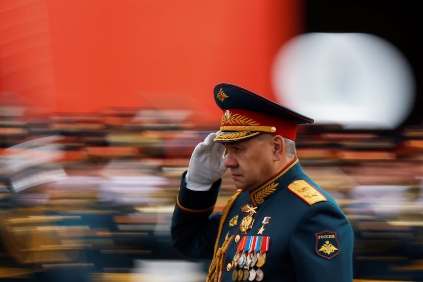 Sergei Shoigu in full military dress salutes a crowd 