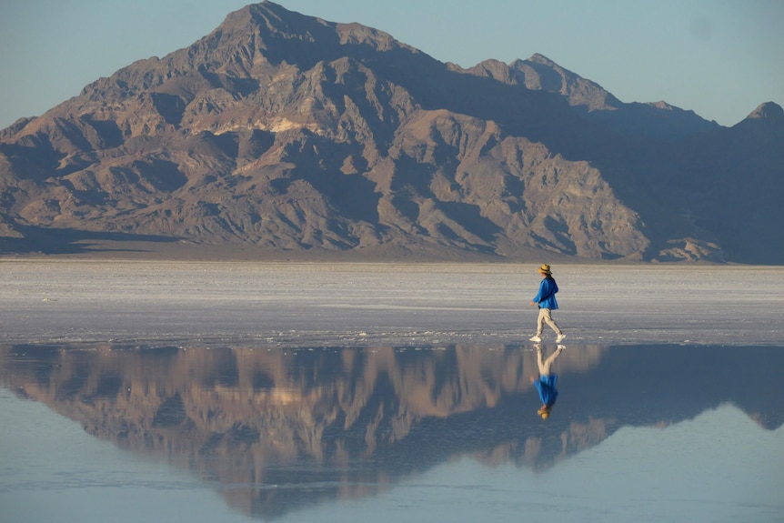 A person who appears to be walking on water in front of a mountain