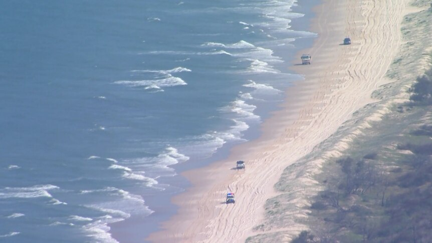 Rescue vehicles drive on a remote beach