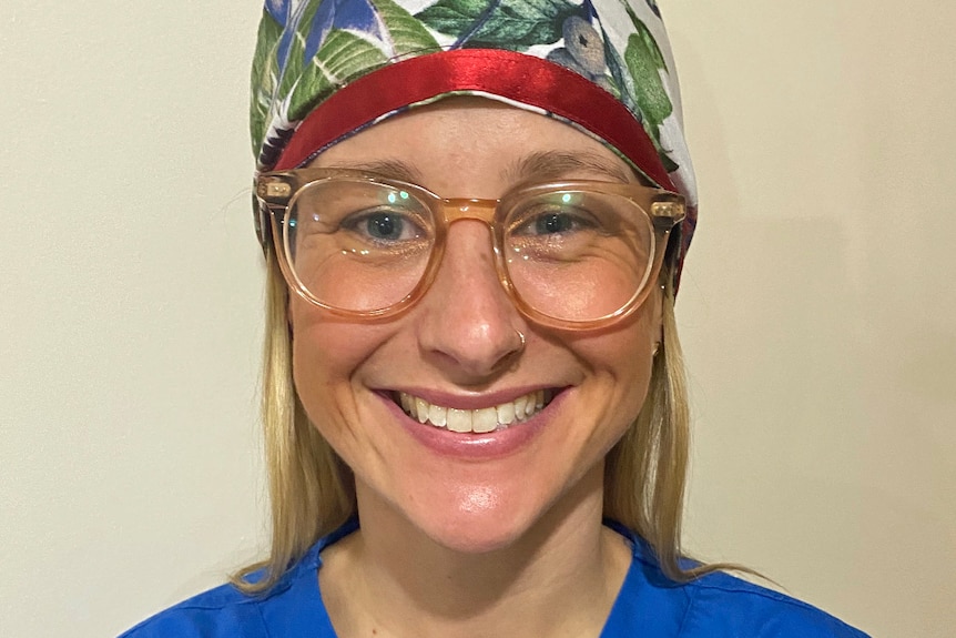 A woman wears a medical cap and gown.