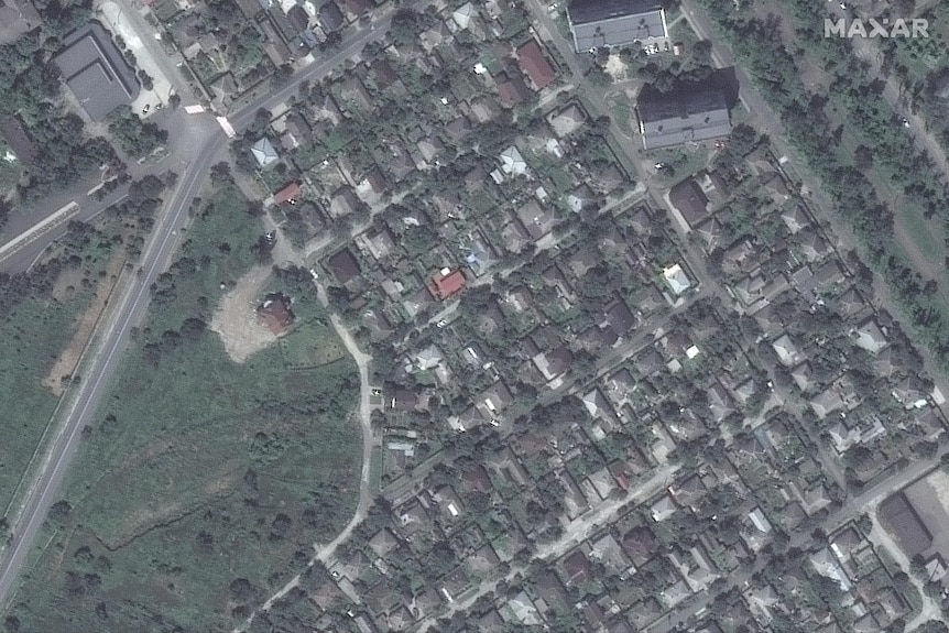 A satellite image shows a top-down view of houses, buildings, roads, trees and parklands.