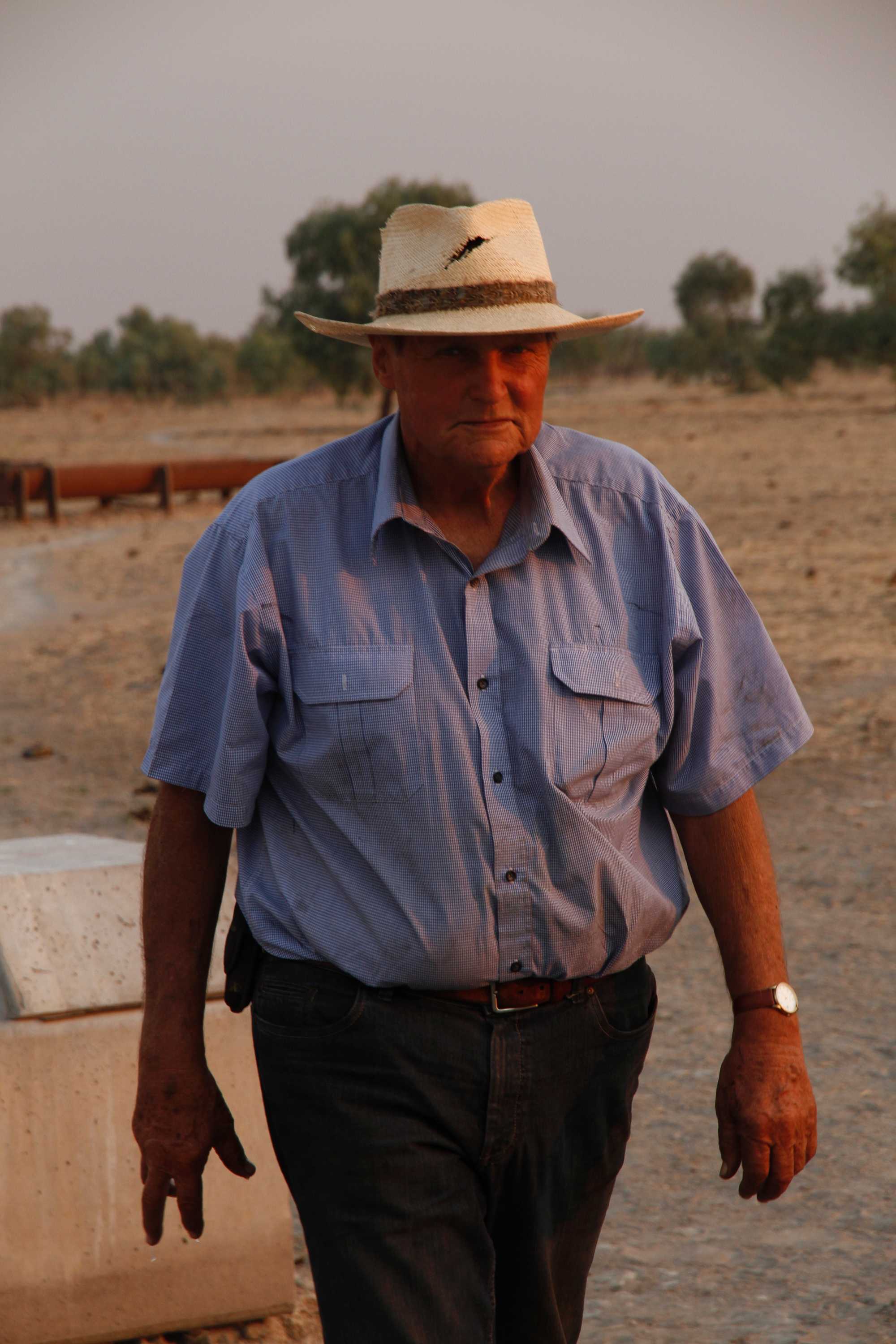 Un hombre mayor con un sombrero blanco roto en un prado.