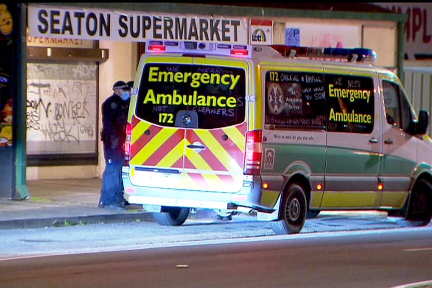 An ambulance and police officers outside a supermarket.