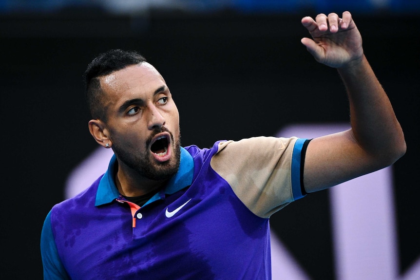 Nick Kyrgios opens his mouth and raises his left arm