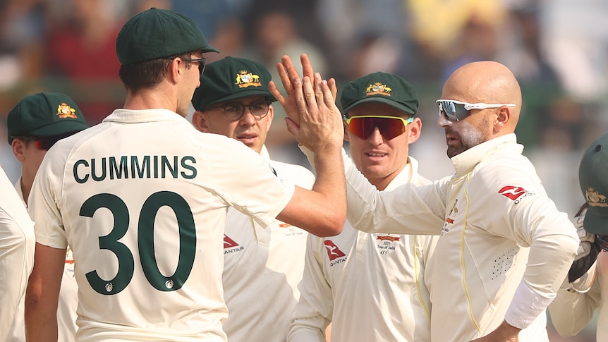 Australian male Test players celebrate Indian wicket.