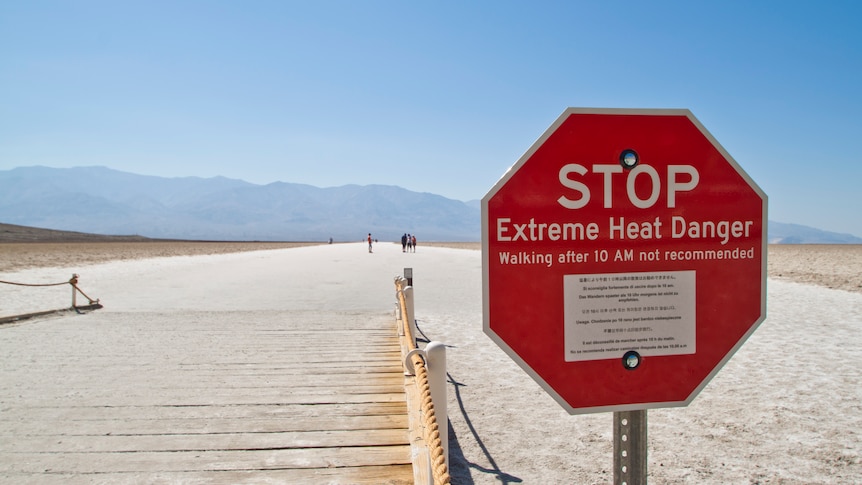 A red stop sign in the desert reading: Stop, Extreme Heat Danger. 