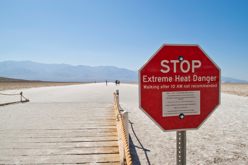 A red stop sign in the desert reading: Stop, Extreme Heat Danger. 