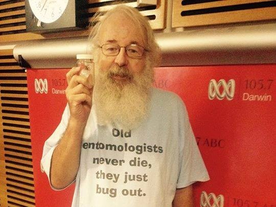 Man in a radio studio holding a jar containing a spider.