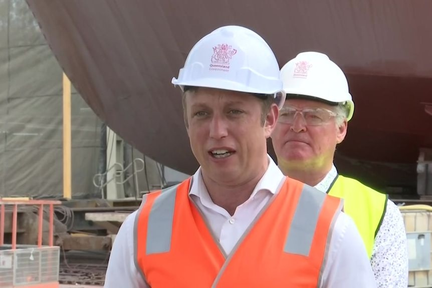 A man in a hard hat and high-vis addressing the media.