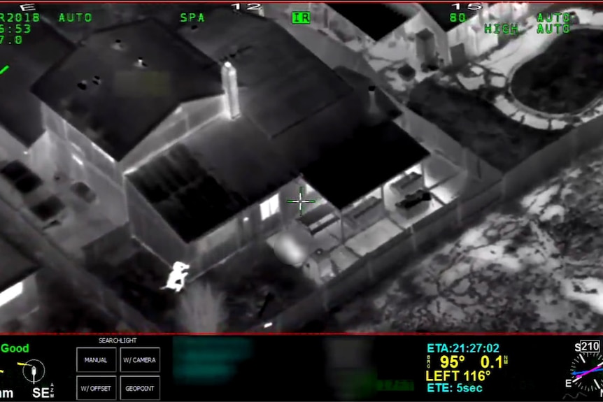 A black and white night-vision screenshot of two police officers pointing guns at a body.