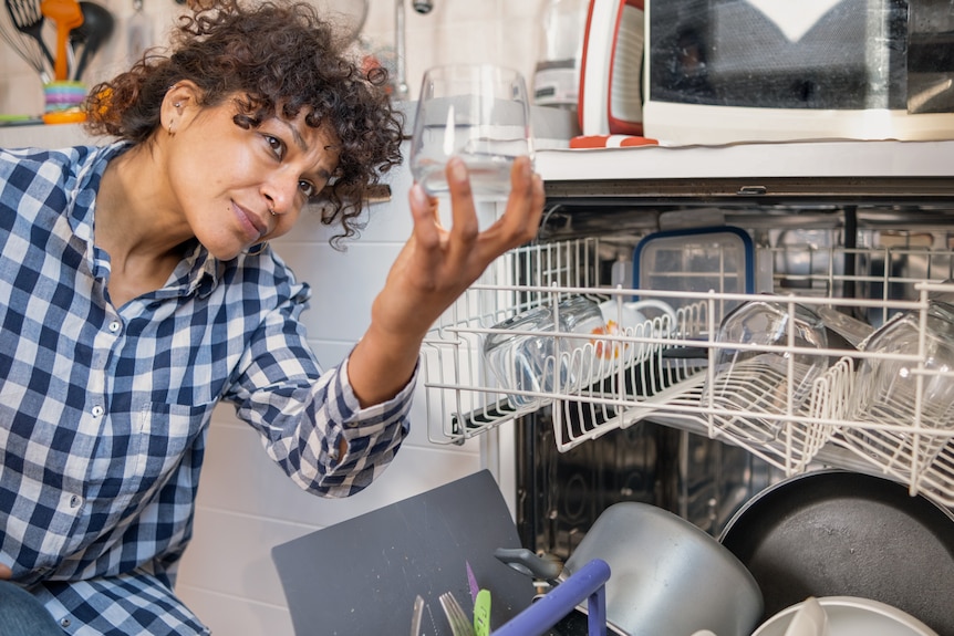 Woman inspecting glass from dishwasher
