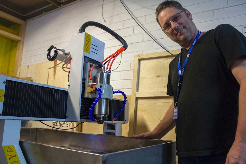 A man stands next to a large machine