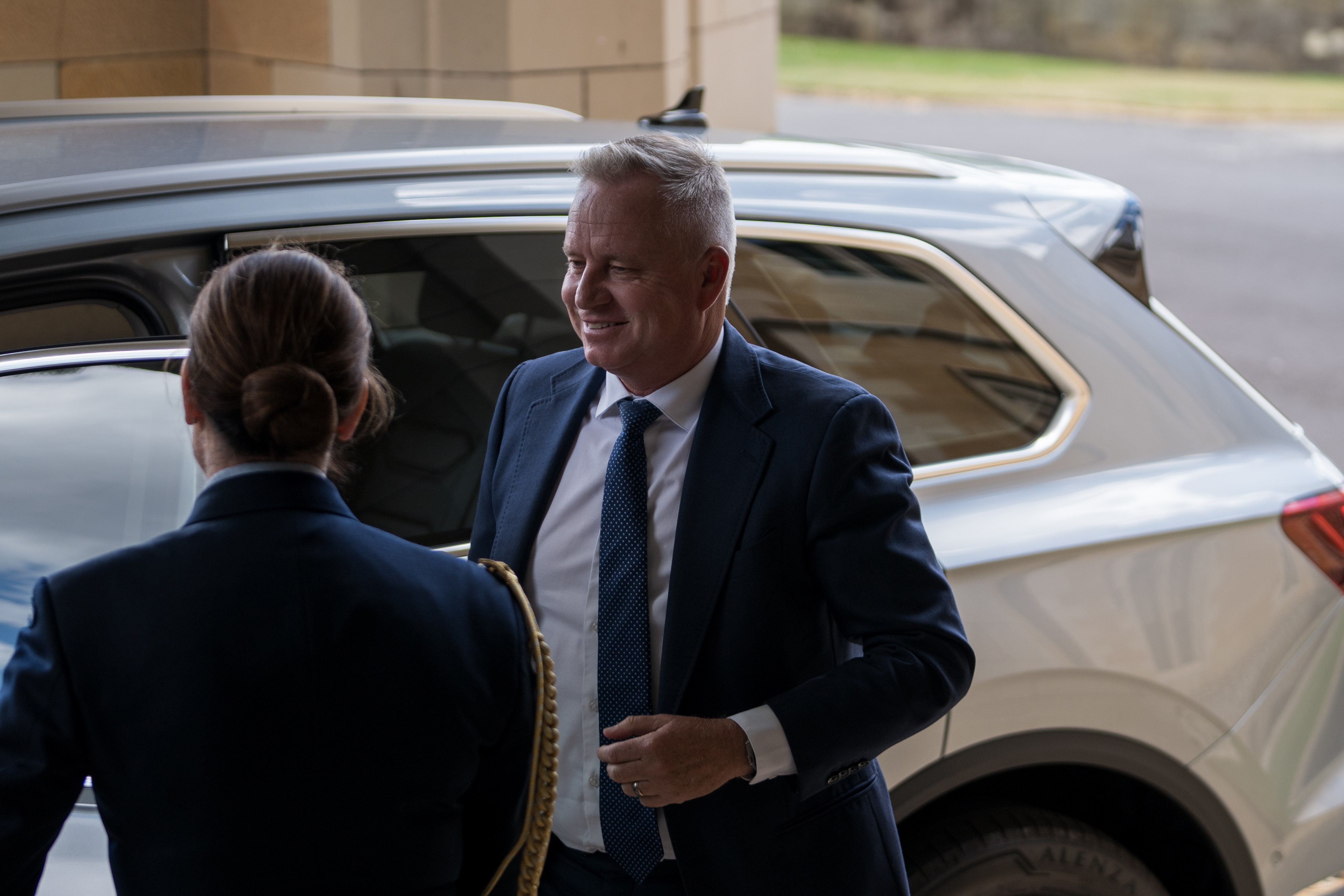 A man smiles as he walks away from a car.
