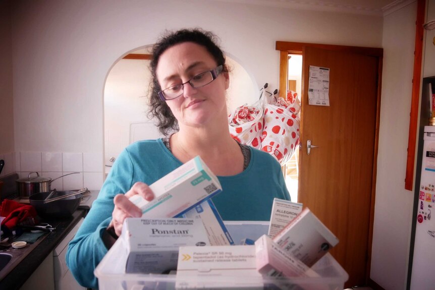 Janelle Gleeson looks at a box of medication.