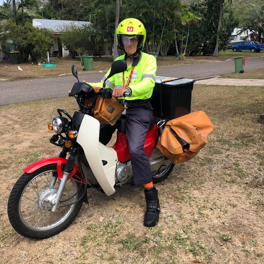 Man sits on motorbike in high viz Australia post uniform