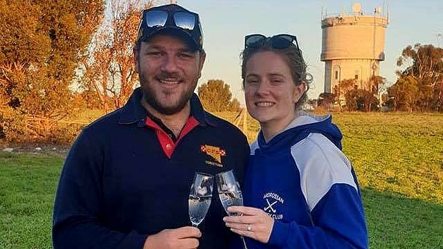 A man and a woman holding champagne flutes in front of a water tower