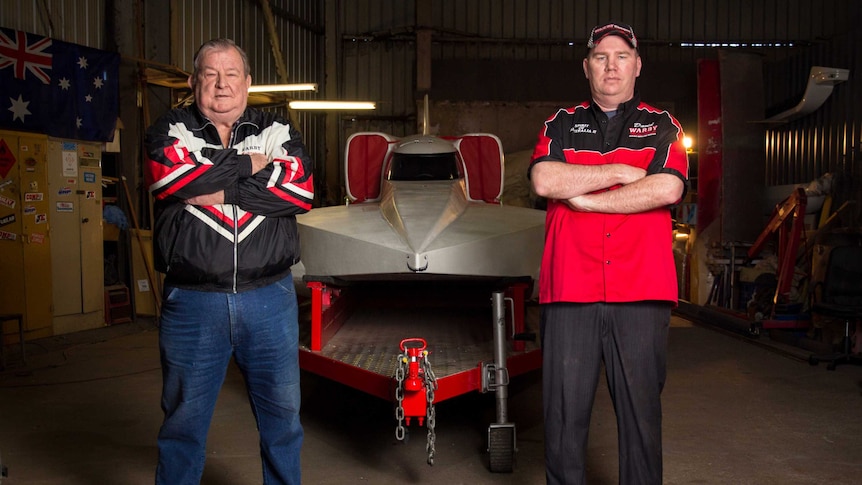 Ken and David Warby stand next to their boat.