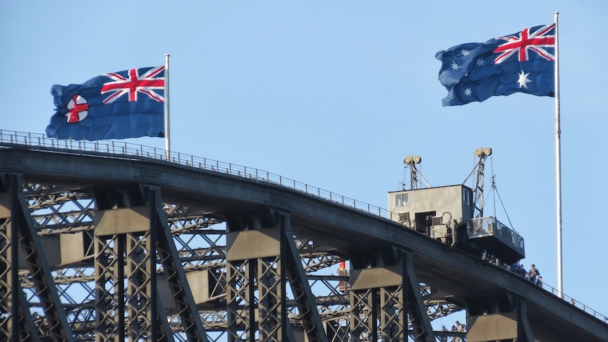 The Australian flag and the NSW flag flying above the Harbour Bridge.