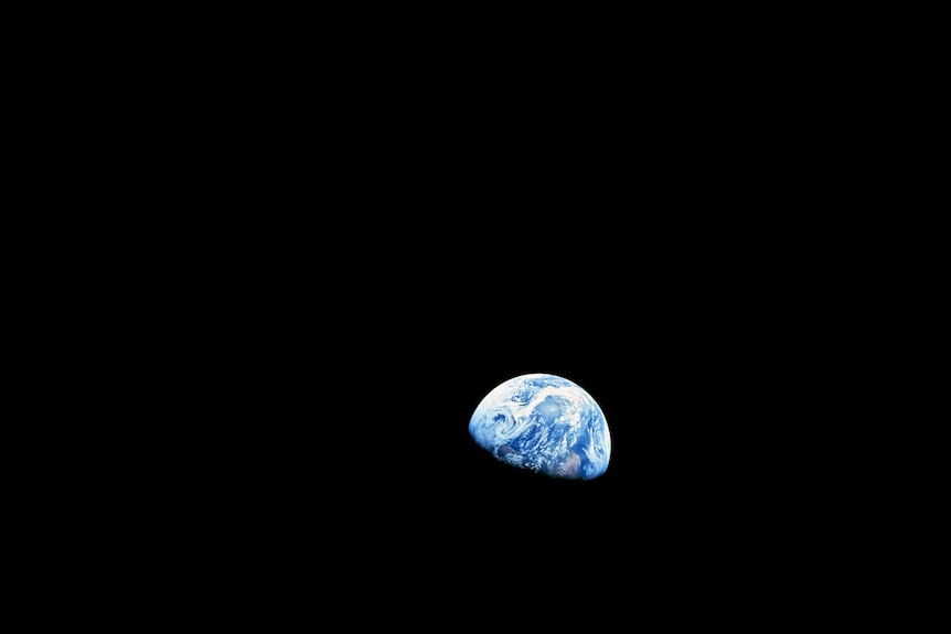 Photo of Earth taken from space, surface of the moon visible in foreground.